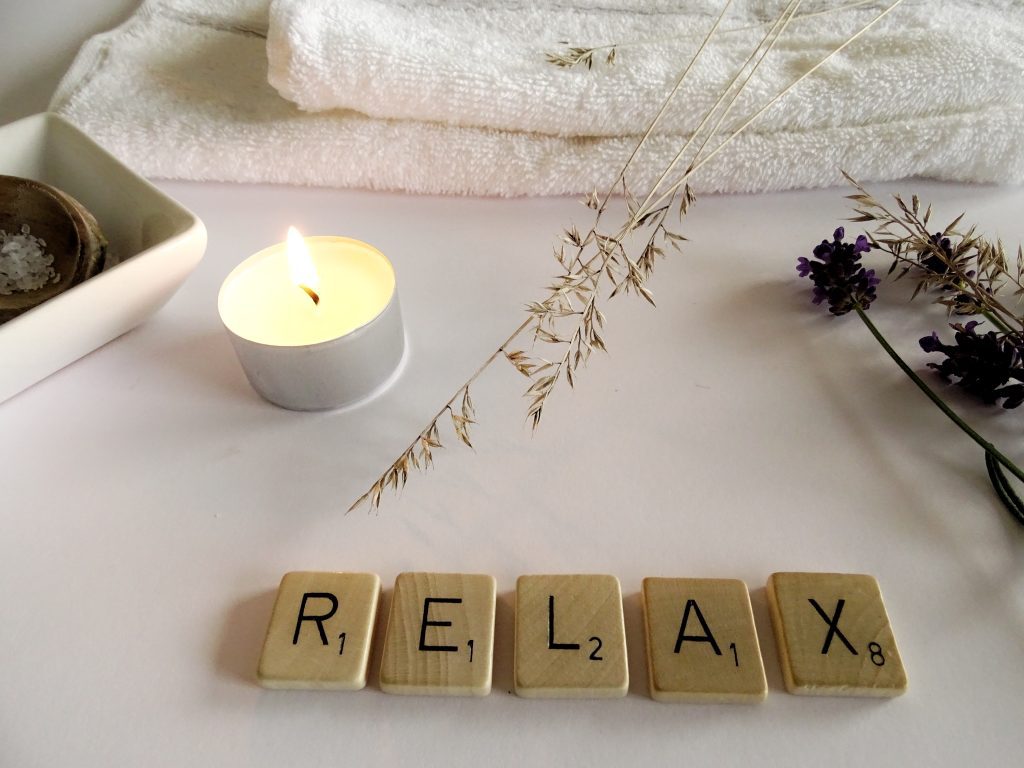 wooden letters that spell "relax" among many relaxing items to emphasize the importance of World Mental Health Day