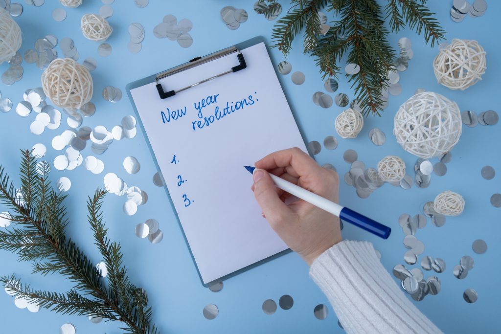 female hands writing new years resolutions goals of 2024